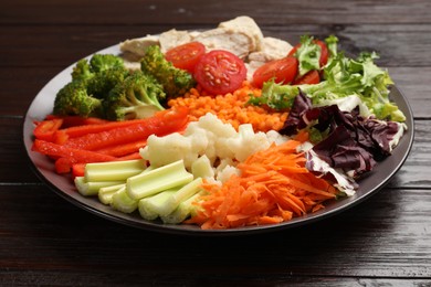 Balanced diet and healthy foods. Plate with different delicious products on dark wooden table, closeup