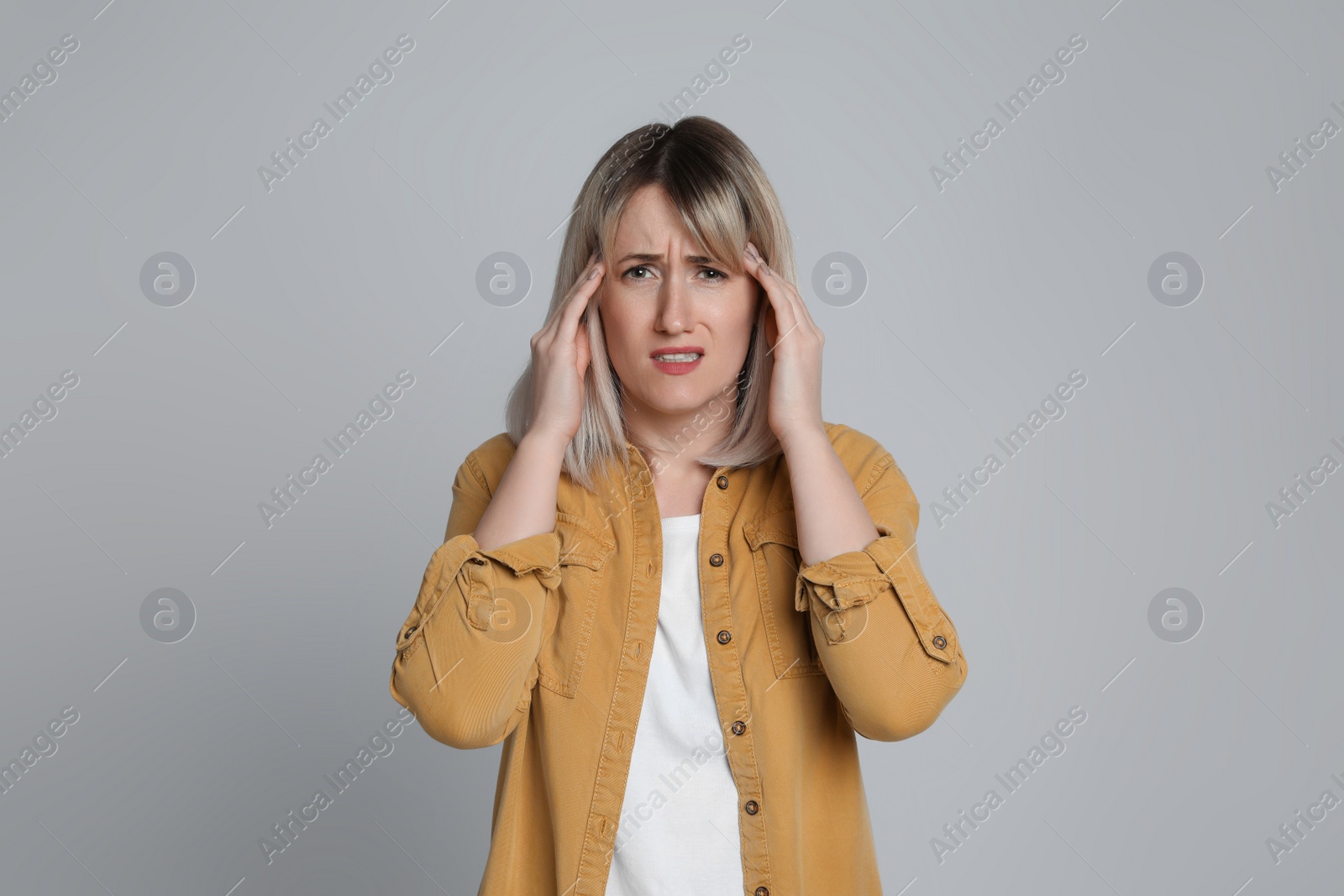 Photo of Woman suffering from headache on light grey background