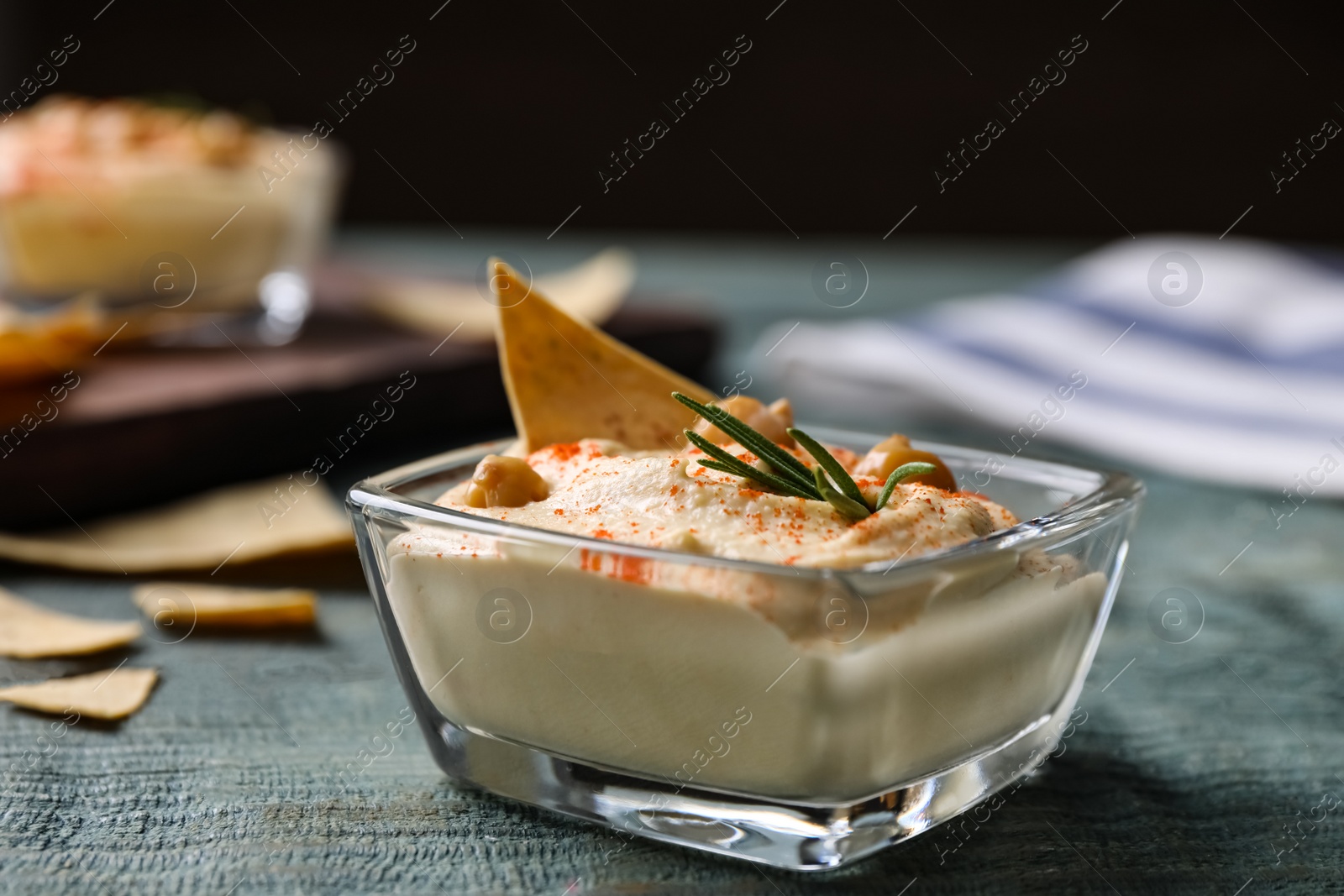 Photo of Delicious homemade hummus in glass bowl on wooden table