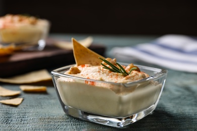 Photo of Delicious homemade hummus in glass bowl on wooden table