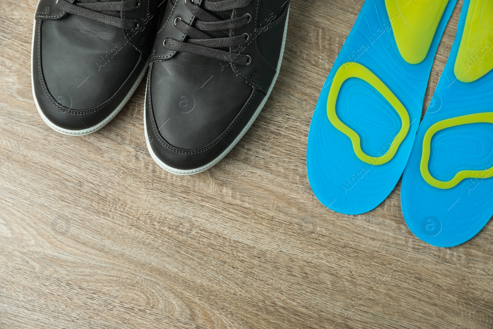 Photo of Orthopedic insoles near shoes on floor, flat lay. Space for text