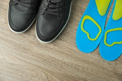 Photo of Orthopedic insoles near shoes on floor, flat lay. Space for text