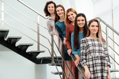 Photo of Portrait of happy ladies on stairs indoors. Women power concept