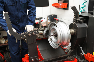 Man working with car disk lathe machine at tire service, closeup