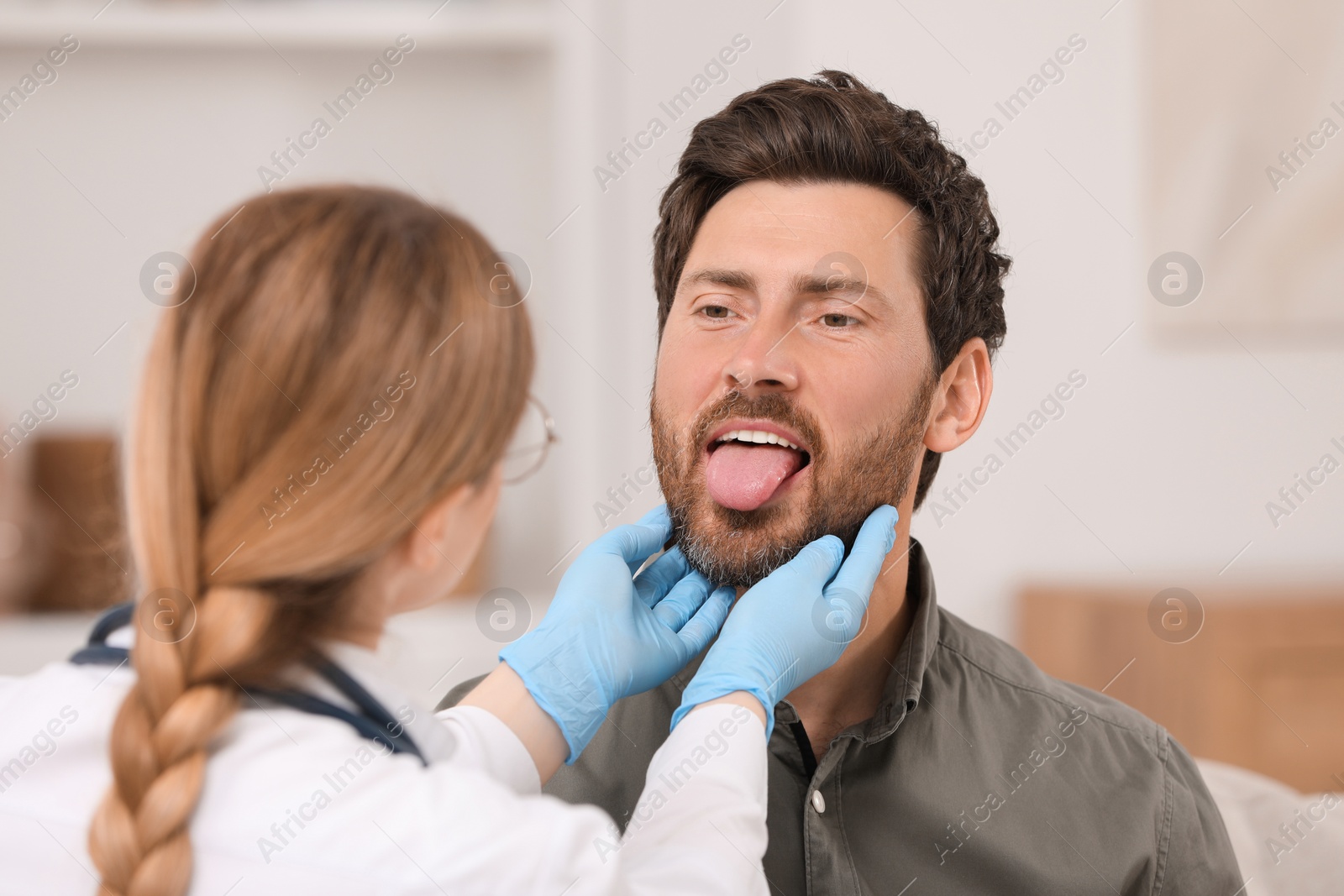 Photo of Doctor in gloves examining man`s oral cavity indoors