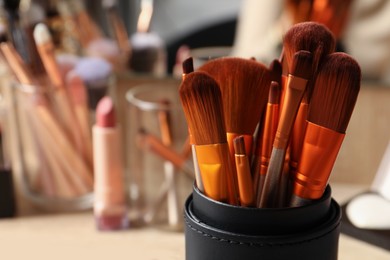 Photo of Setprofessional brushes and makeup products near mirror, closeup. Space for text