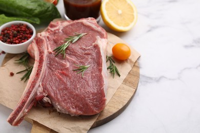 Photo of Raw meat, rosemary and products on white marble table, closeup. Space for text
