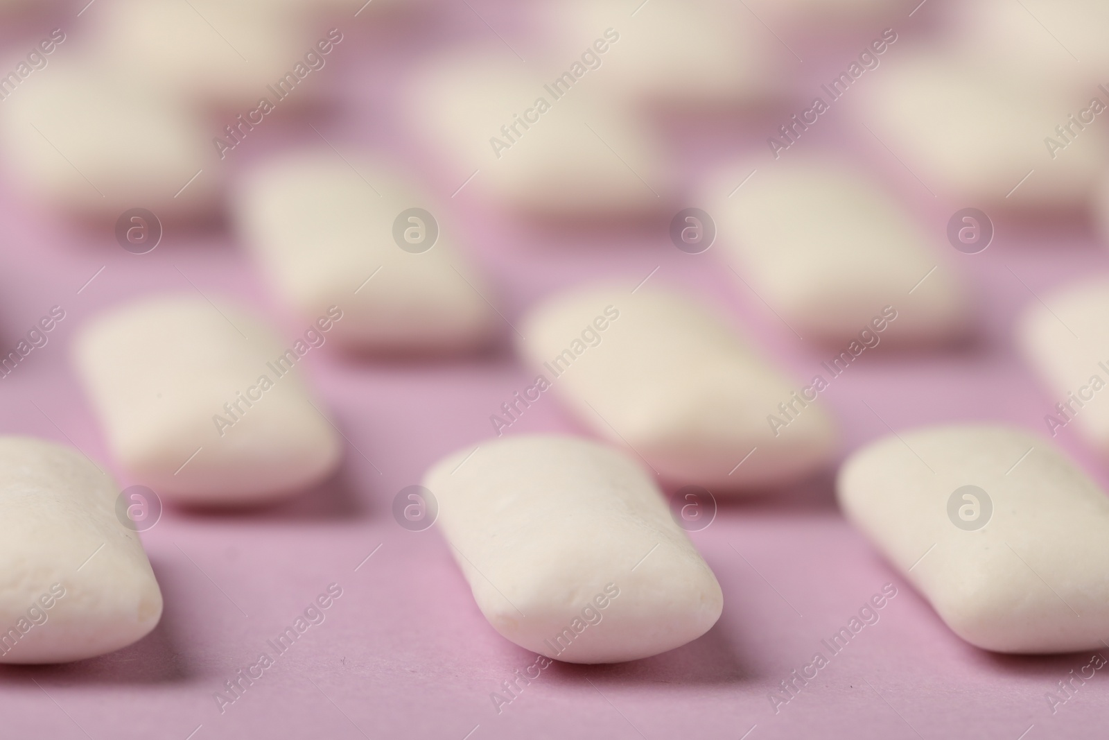 Photo of Many chewing gum pieces on pink background, closeup