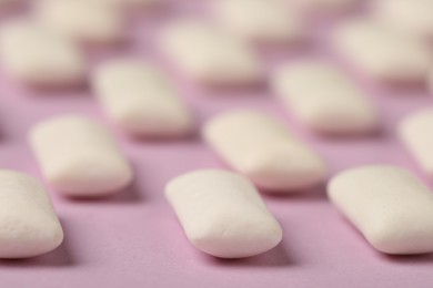 Many chewing gum pieces on pink background, closeup