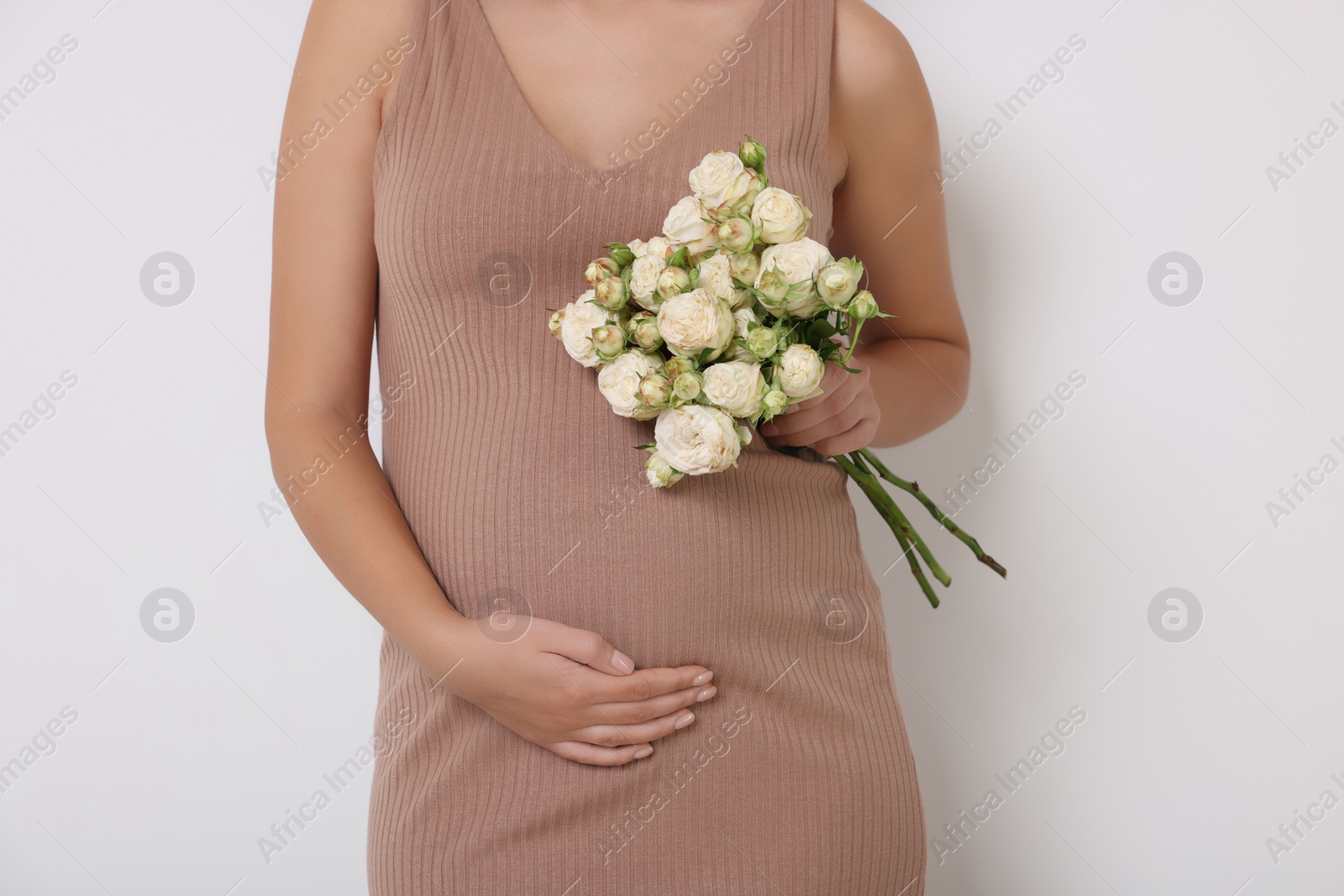 Photo of Pregnant woman in beige dress with bouquet of roses on white background, closeup