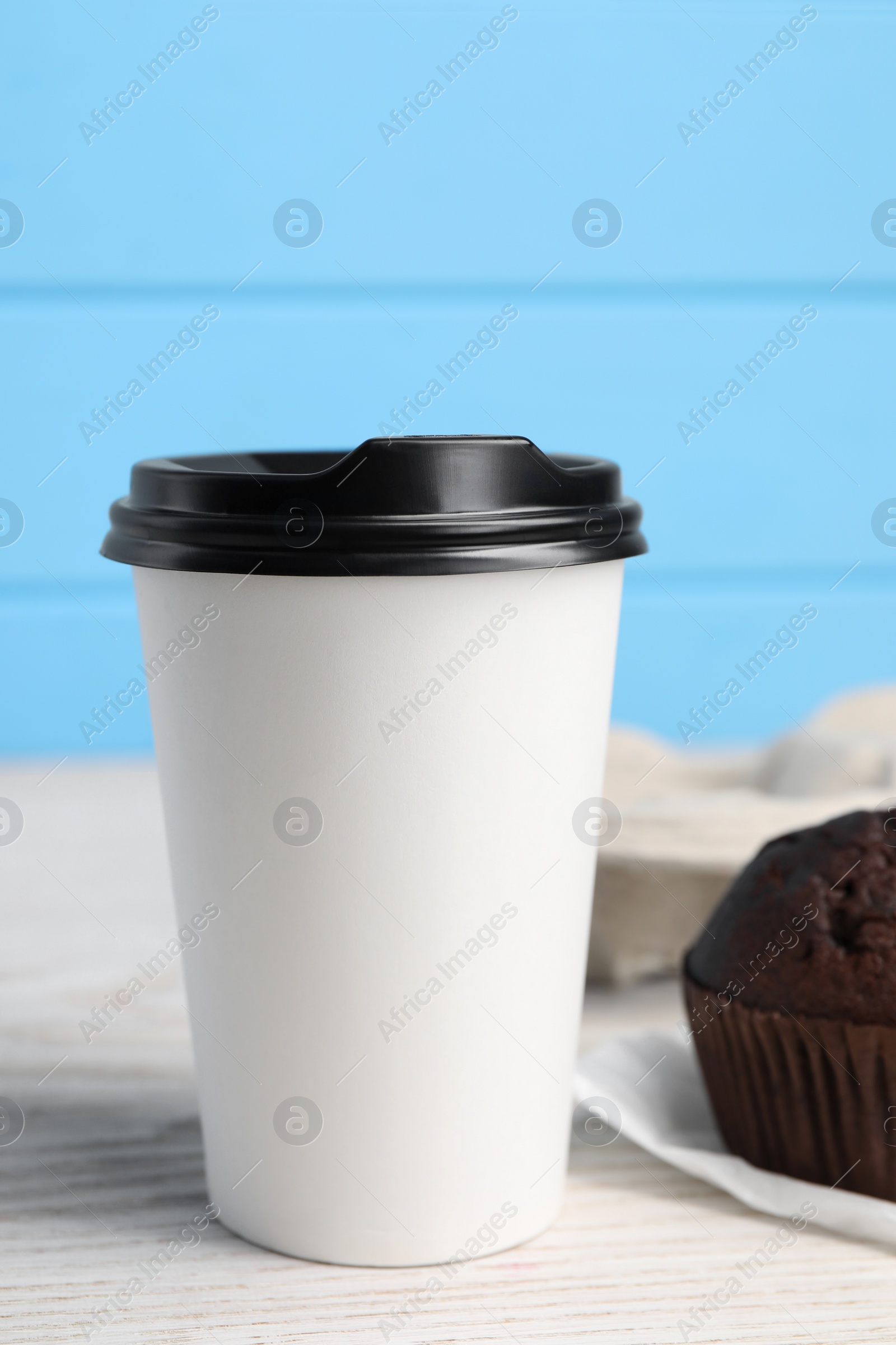 Photo of Paper cup with black lid on white wooden table. Coffee to go