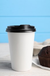 Photo of Paper cup with black lid on white wooden table. Coffee to go