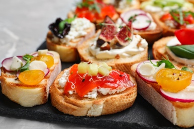 Different bruschettas on light grey marble table, closeup