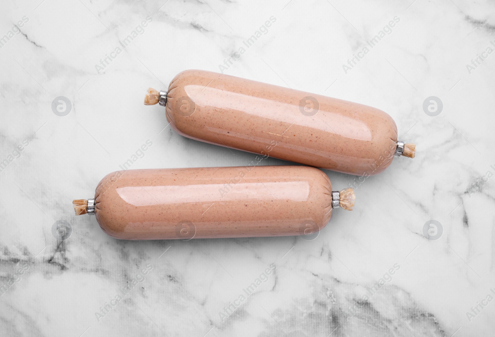 Photo of Delicious liver sausages on white marble table, flat lay