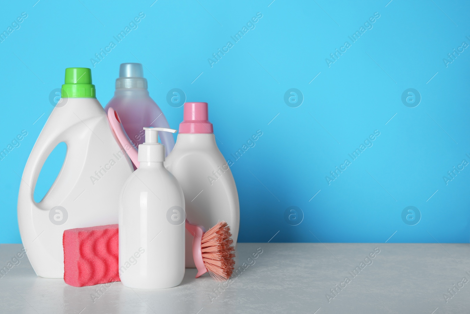 Photo of Different cleaning supplies and tools on table against light blue background, space for text