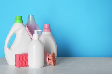 Photo of Different cleaning supplies and tools on table against light blue background, space for text