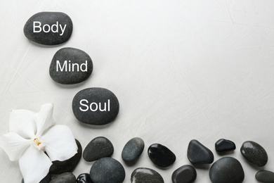 Stones with words MIND, BODY, SOUL on light background, top view and space for text. Zen lifestyle