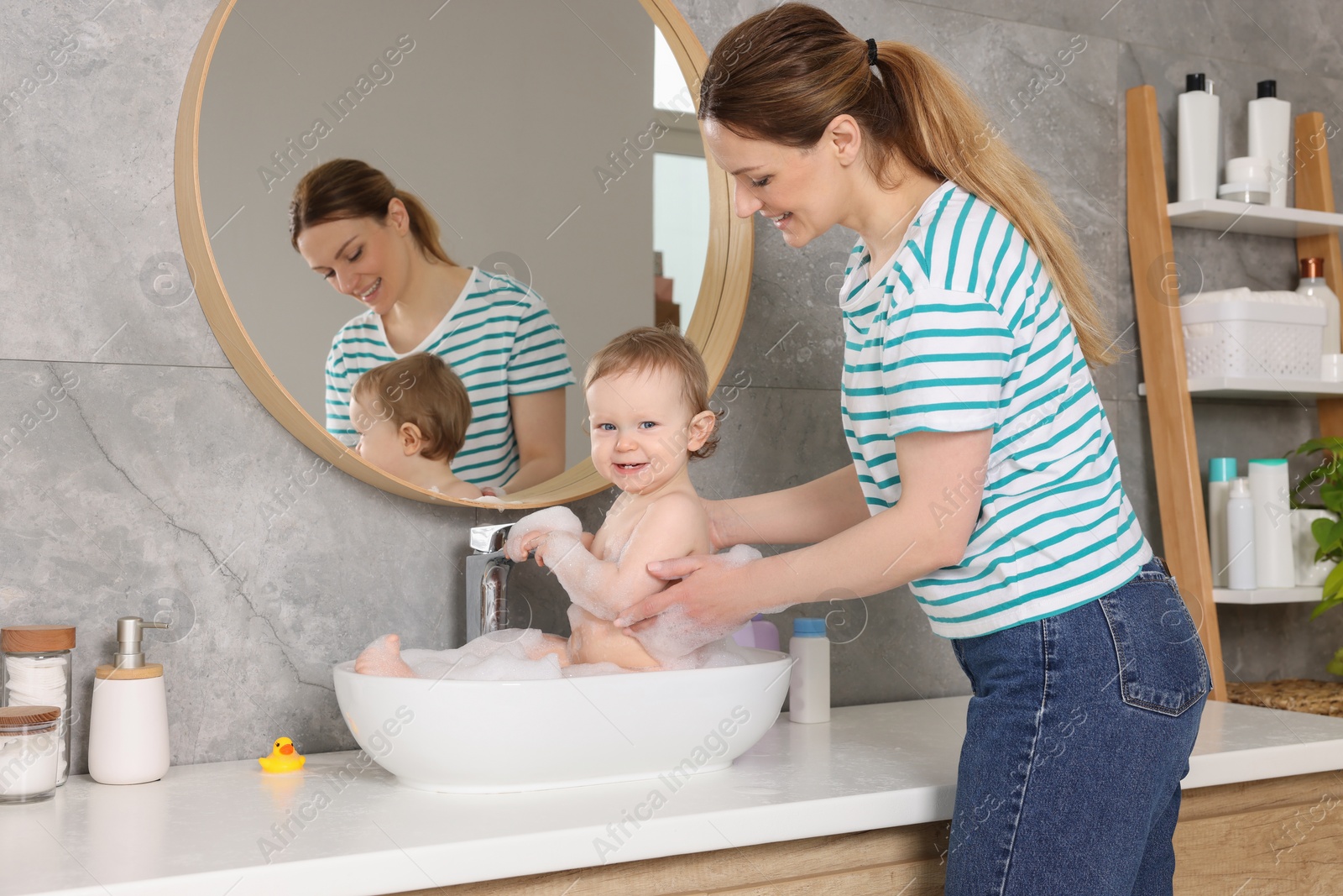 Photo of Mother washing her little baby in sink at home