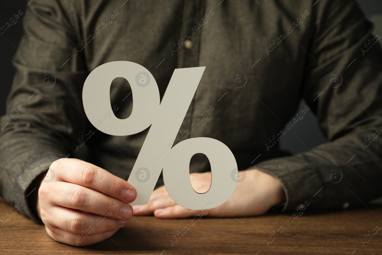 Photo of Man holding percent sign at wooden table, closeup