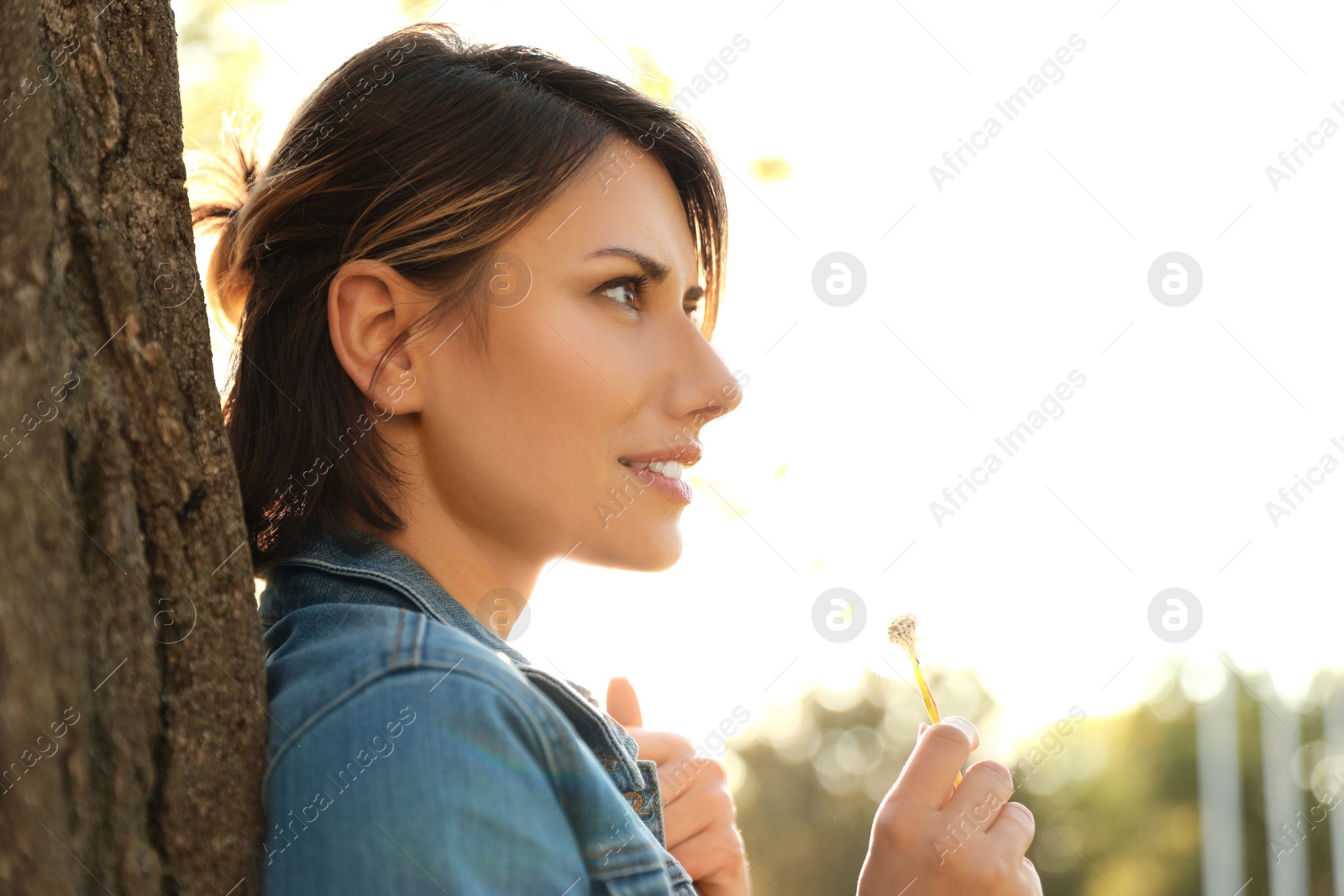 Photo of Young woman with dandelion in park on sunny day. Allergy free concept