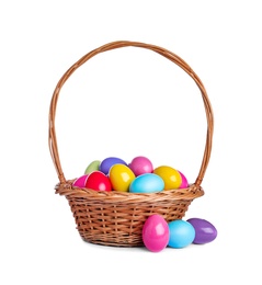 Photo of Wicker basket with bright painted Easter eggs on white background