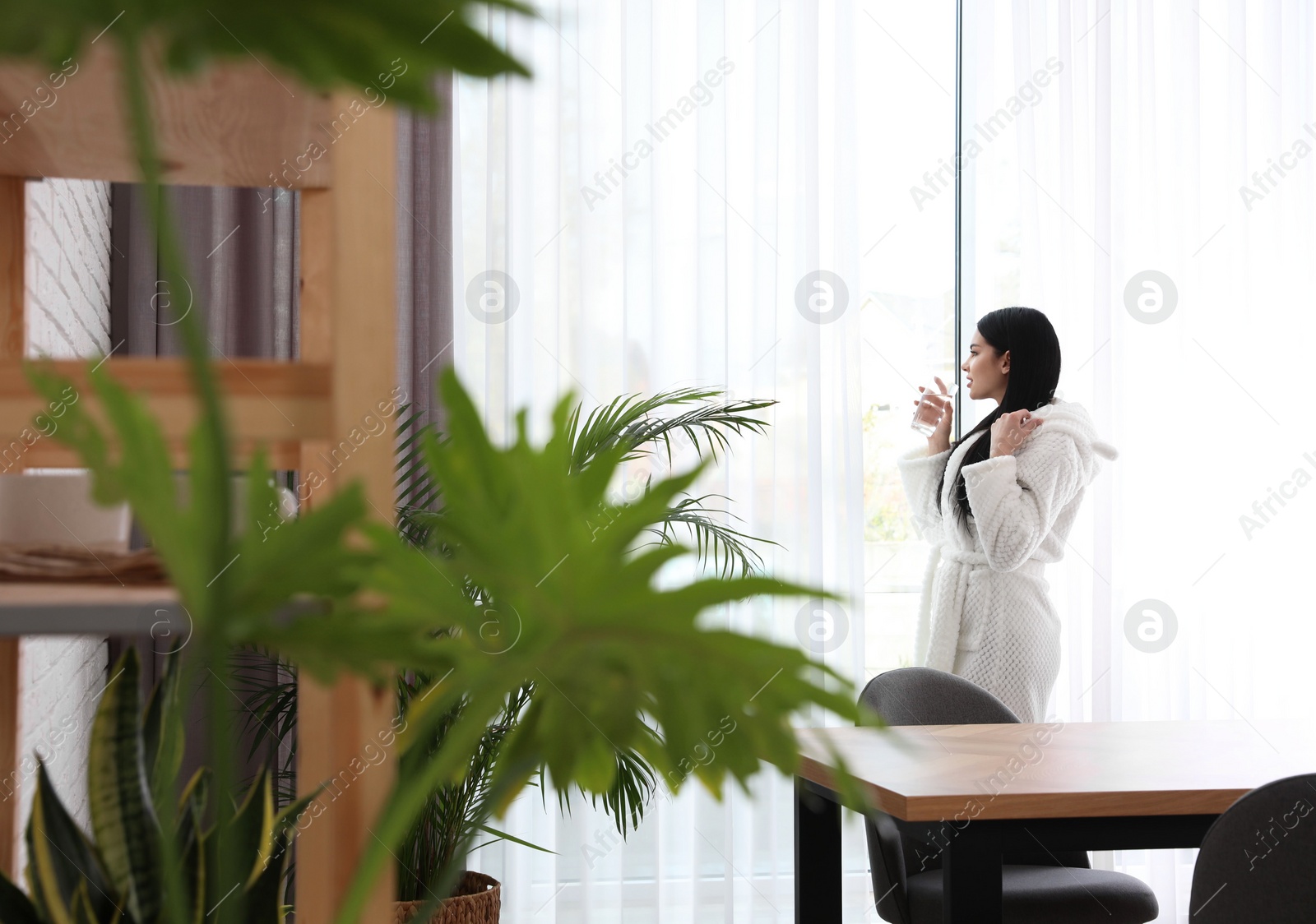 Photo of Woman near window in room decorated with plants. Home design ideas