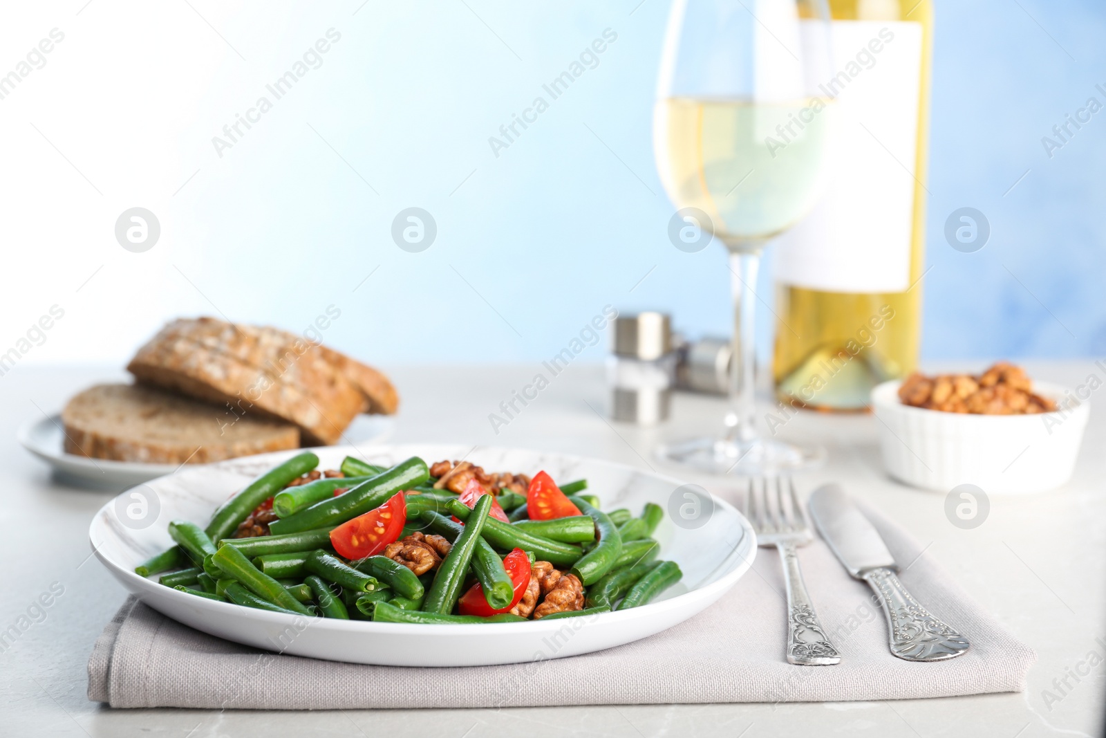 Photo of Tasty green beans with walnuts and tomatoes served for dinner on table