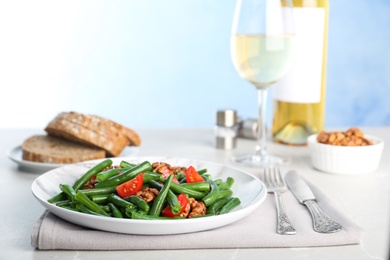 Tasty green beans with walnuts and tomatoes served for dinner on table