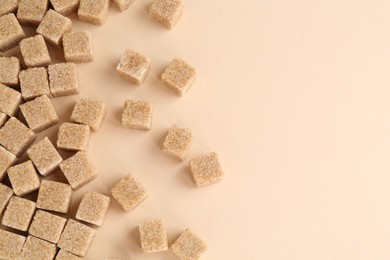 Photo of Brown sugar cubes on beige background, top view. Space for text