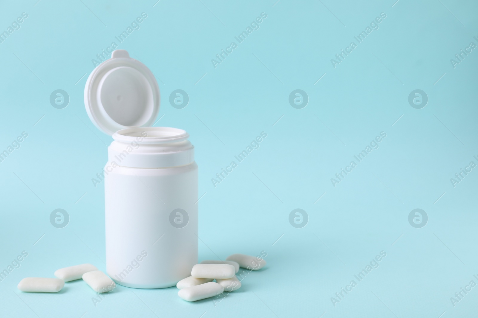 Photo of Jar with chewing gums on light blue background. Space for text