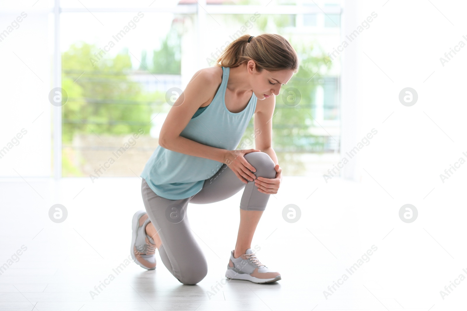 Photo of Woman in sportswear suffering from knee pain at gym