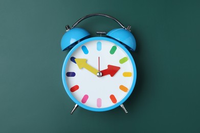 Photo of Alarm clock on green chalkboard, top view. School time