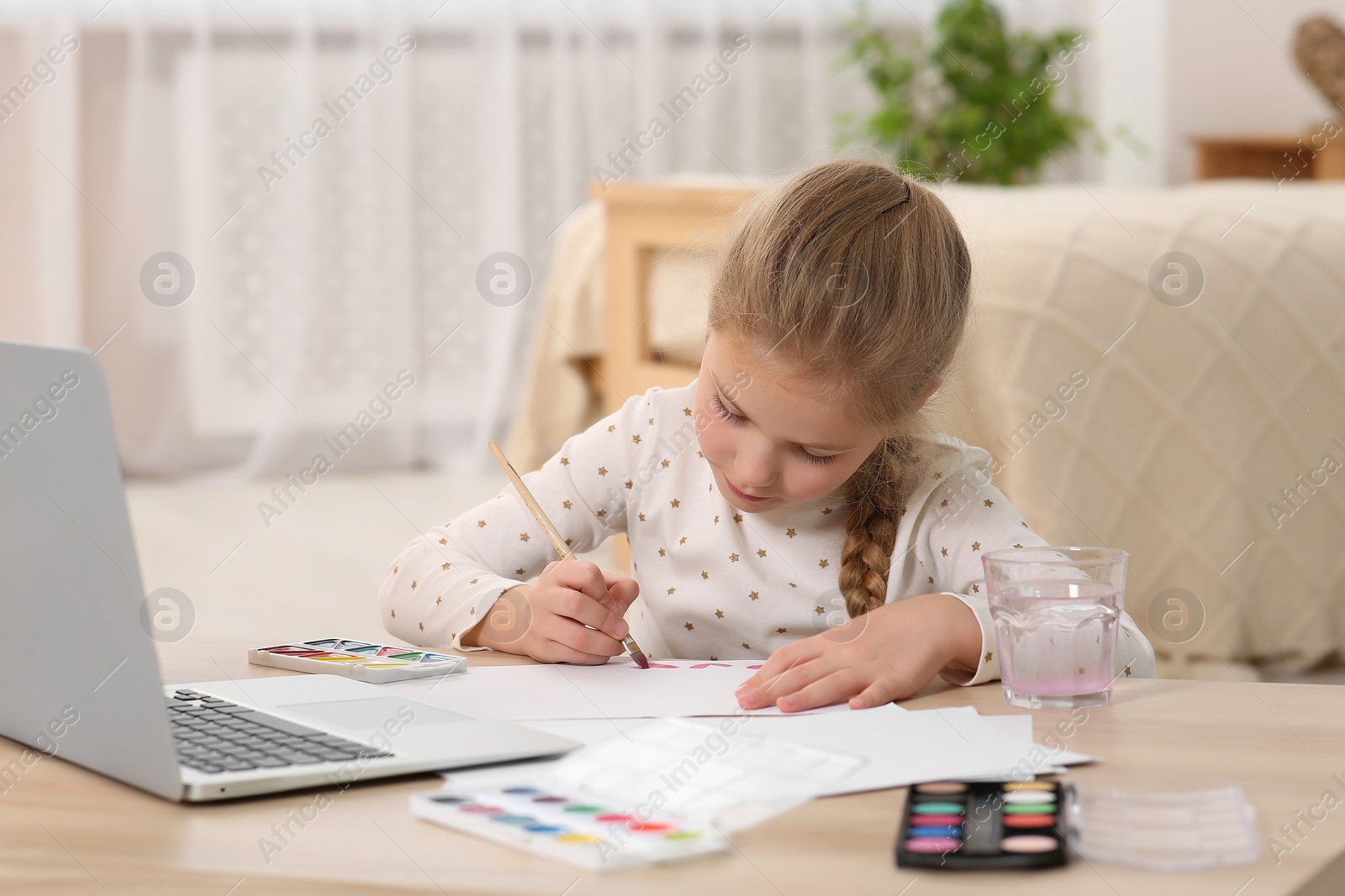 Photo of Little girl learning to paint with online course at home. Time for hobby