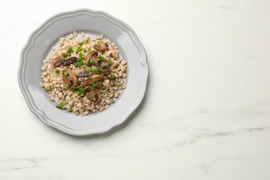 Photo of Delicious pearl barley with onion and mushrooms on white marble table, top view. Space for text