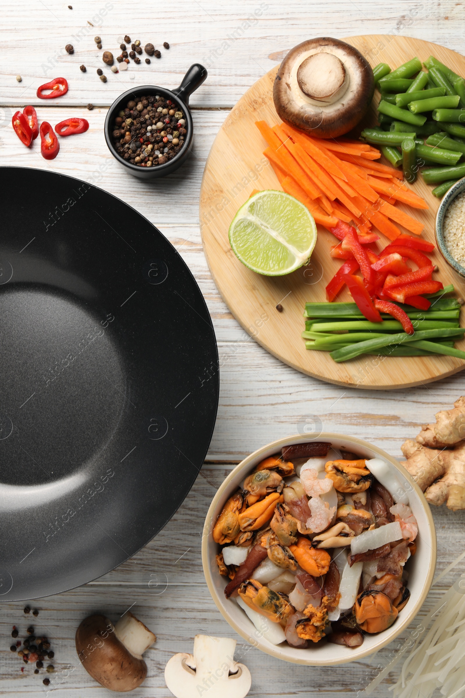 Photo of Flat lay composition with black wok and products on light wooden table