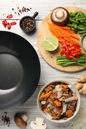 Flat lay composition with black wok and products on light wooden table