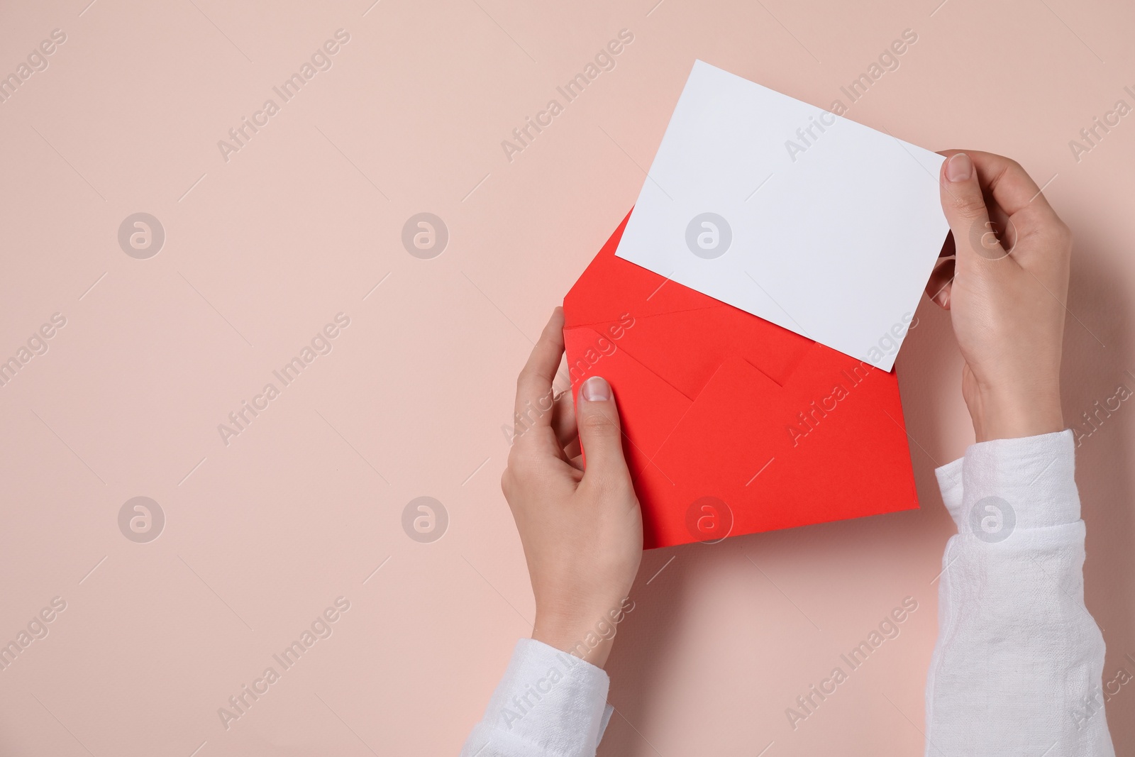 Photo of Woman taking card out of letter envelope at beige table, top view. Space for text