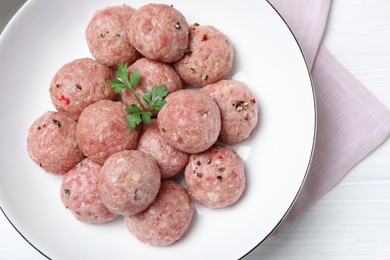 Many fresh raw meatballs on white wooden table, flat lay