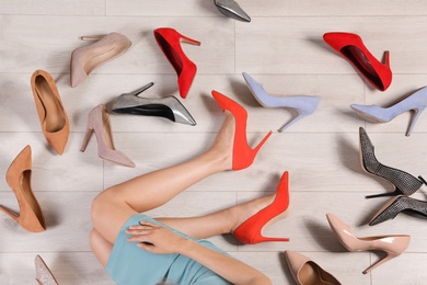 Woman and different stylish shoes on wooden floor, top view