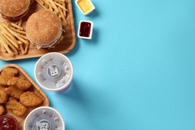 Different fast food on turquoise background, flat lay. Space for text