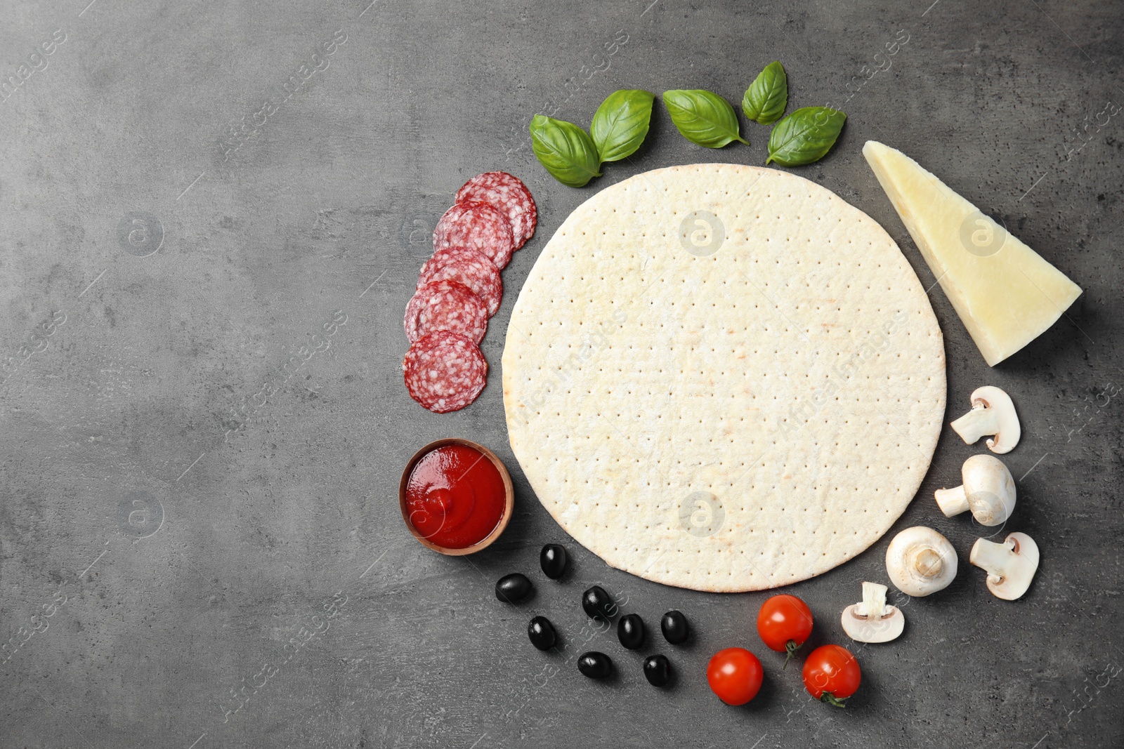 Photo of Flat lay composition with base and ingredients for pizza on grey table, space for text