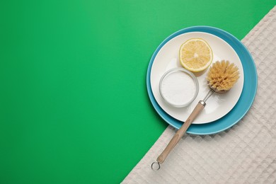 Photo of Tableware and cleaning supplies for washing dishes on green background, top view