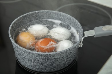 Boiling chicken eggs in saucepan on electric stove