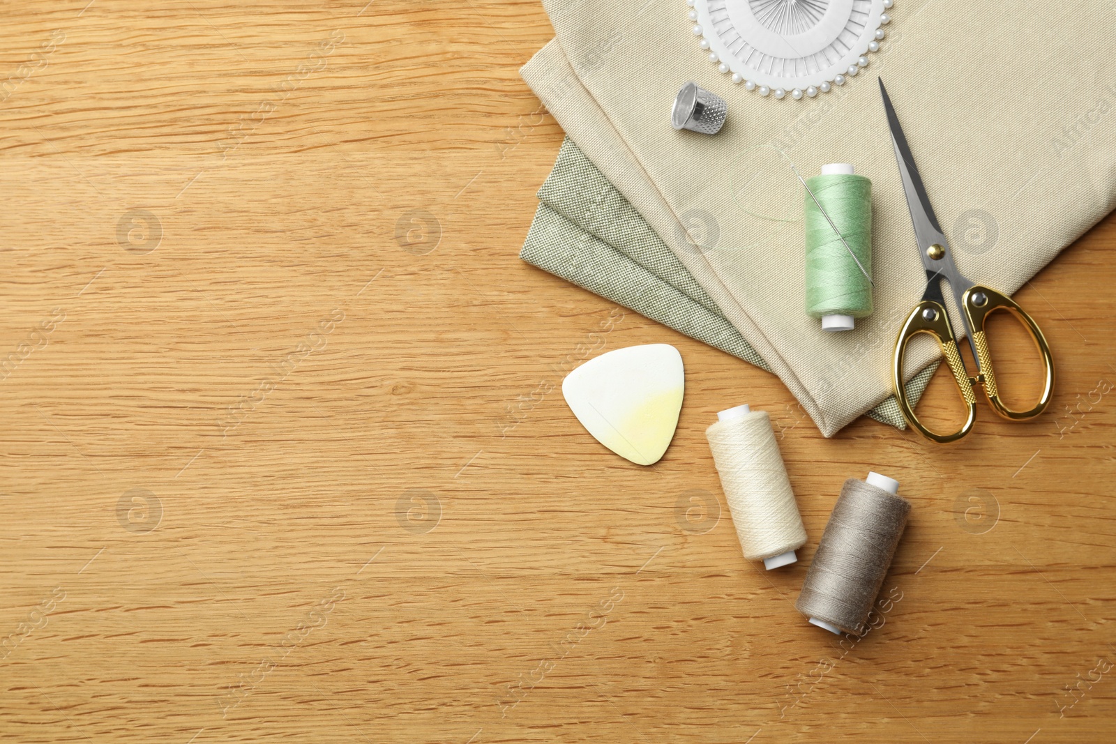 Photo of Flat lay composition with spool of threads and sewing tools on wooden table. Space for text