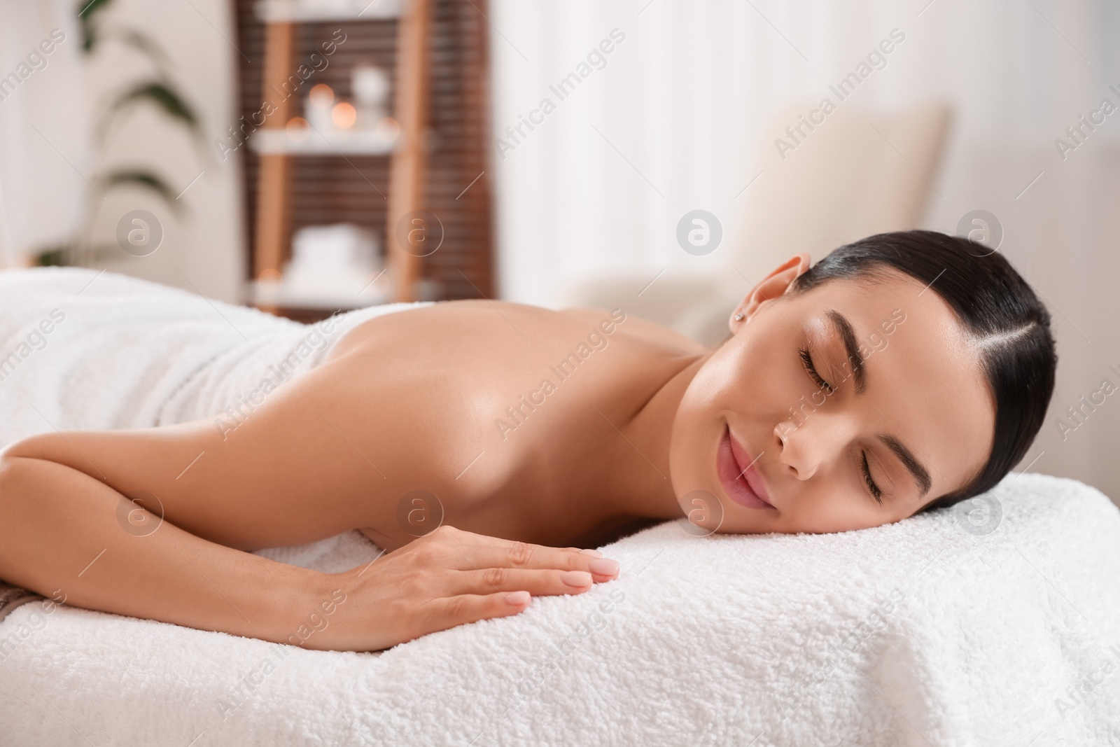 Photo of Young woman resting on massage couch in spa salon