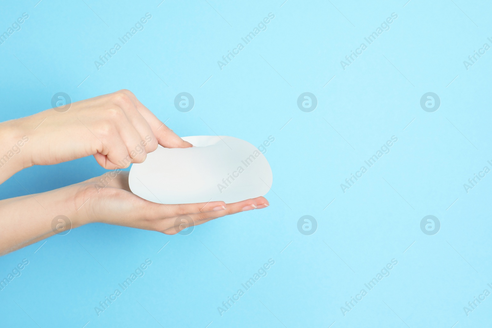 Photo of Woman touching silicone implant for breast augmentation on color background, space for text. Cosmetic surgery