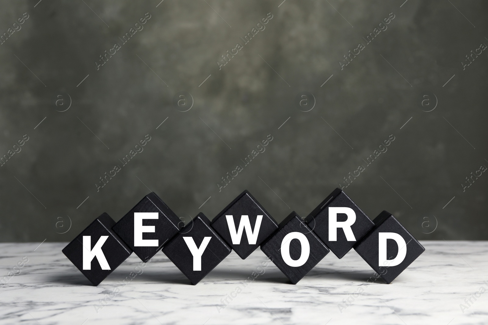 Photo of Black cubes with word KEYWORD on white marble table. Space for text