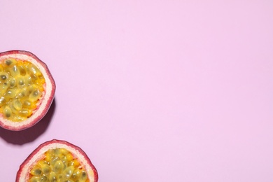 Halves of passion fruit (maracuya) on pink background, flat lay. Space for text