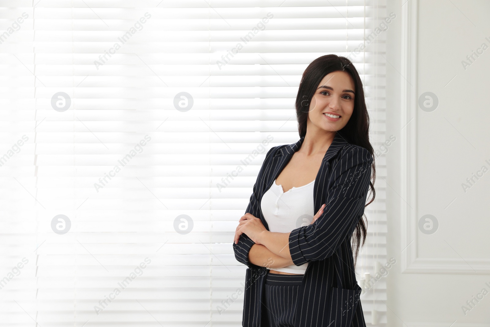 Photo of Beautiful woman in formal suit near window, space for text. Business attire