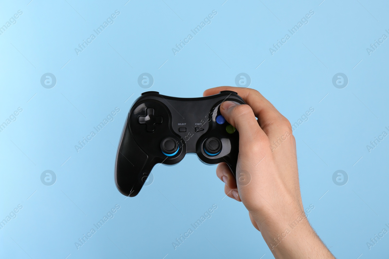 Photo of Man using wireless game controller on light blue background, closeup